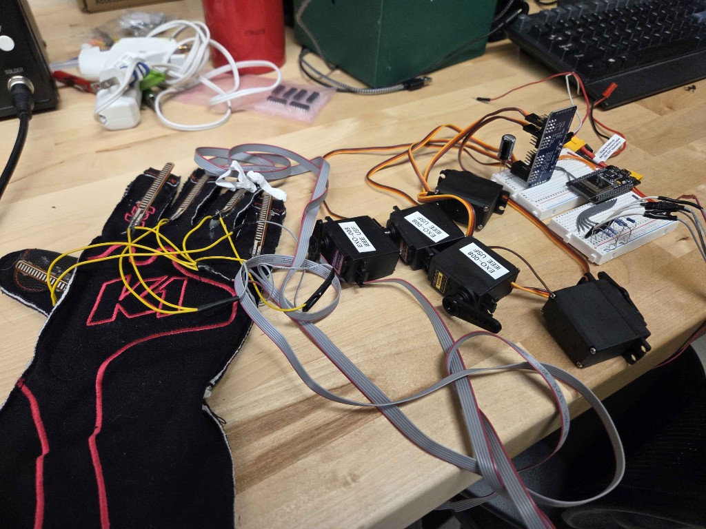 EXO mimetic robotic hand prototype with flex sensors on a glove, servos, and control circuitry on a workbench