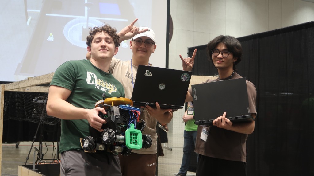 Three IEEE at USF students holding their SoutheastCon competition robot and laptops